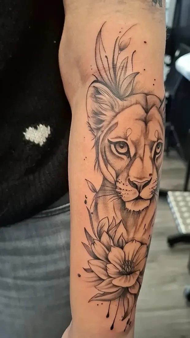Löwenkopf mit Blüten in feinen Linien am Oberarm